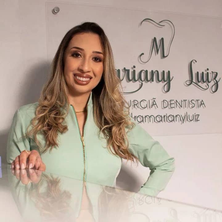 Dra. Mariany Luiz na clínica de Cachoeirinha, ao lado da placa Mariany Luiz - Cirurgiã Dentista